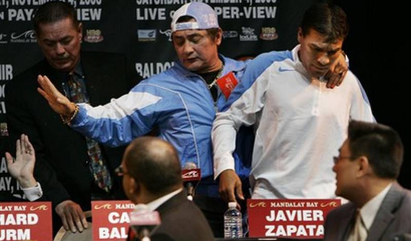 Тренер Хавьер Запата придерживает Карлоса Бальдомира после стычки с командой Флойда Мэйвезера на пресс-конференции в Лас-Вегасе