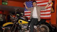 Джо Калзаге с американским флагом на оригинальном мотоцикле из фильма "Рокки-3" во время пресс-конференции в Лондоне